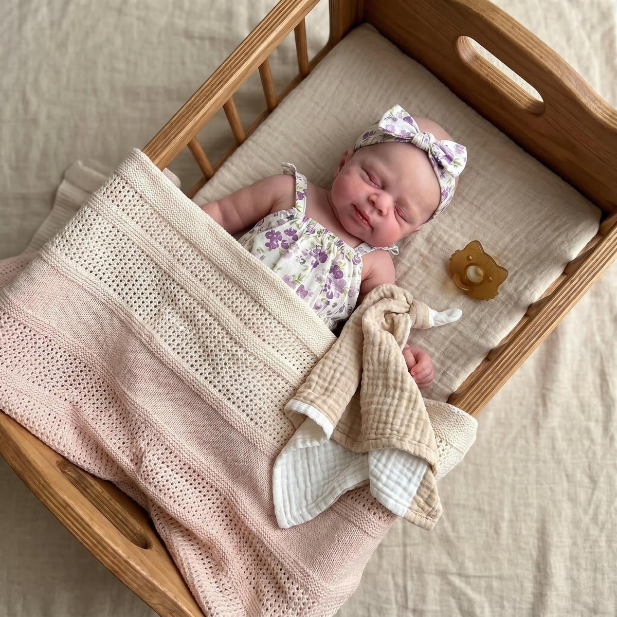 30 cm Pascale Reborn Puppe aus Vollsilikon mit geschlossenen Augen im lila geblümten Strampler