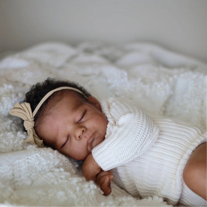 50 cm Reborn Puppe Eric mit geschlossenen Augen dunkler Haut und kurzem Haar im weißen Pullover