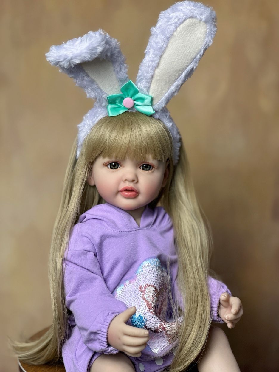 55 cm wiedergeborenes Mädchen mit offenen Augen und langen Haaren in lila Kleidung und Hasenohren-Haarreif - Betty