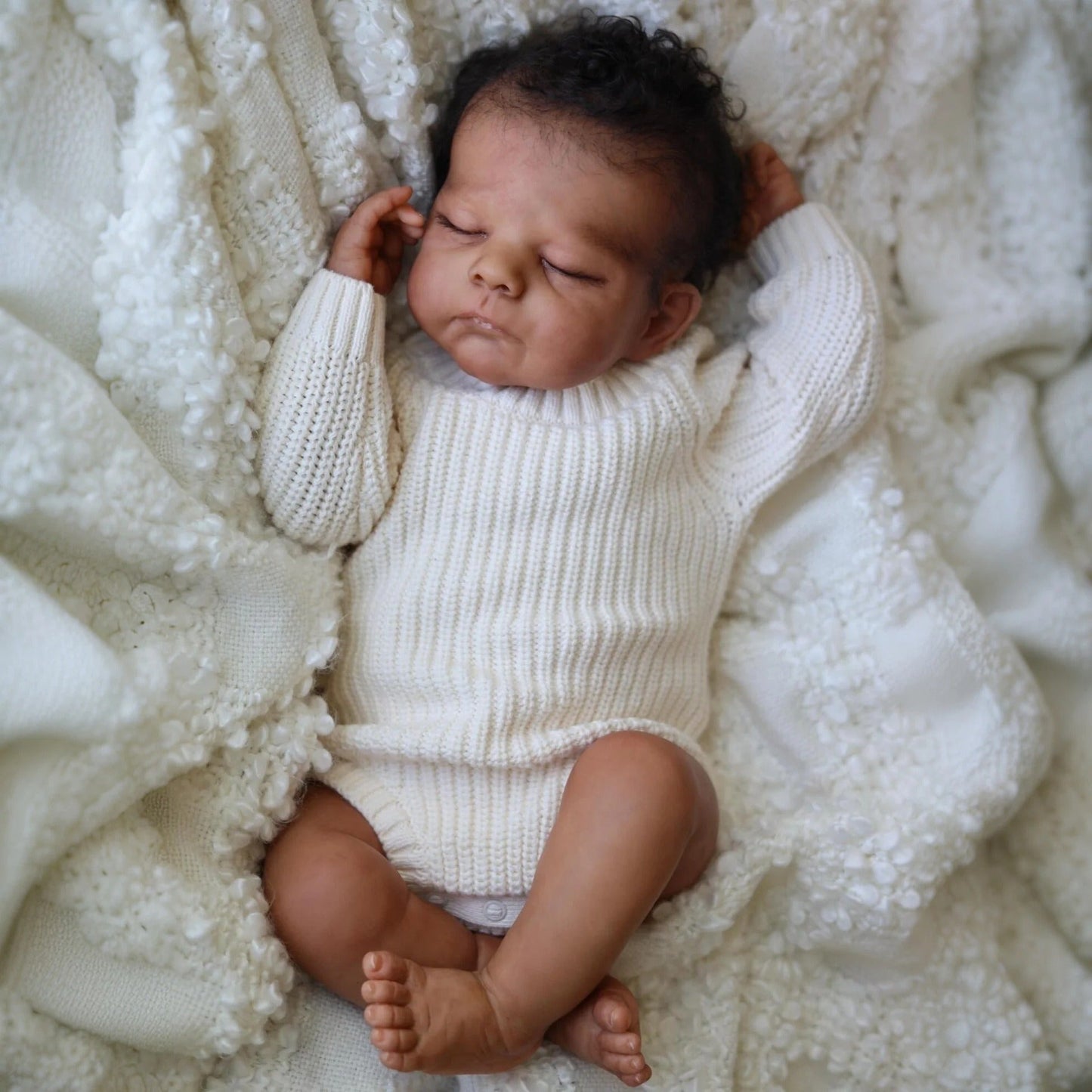 50 cm Reborn Puppe Eric mit geschlossenen Augen dunkler Haut und kurzem Haar im weißen Pullover