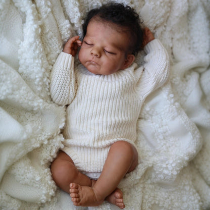 50 cm Reborn Puppe Eric mit geschlossenen Augen dunkler Haut und kurzem Haar im weißen Pullover